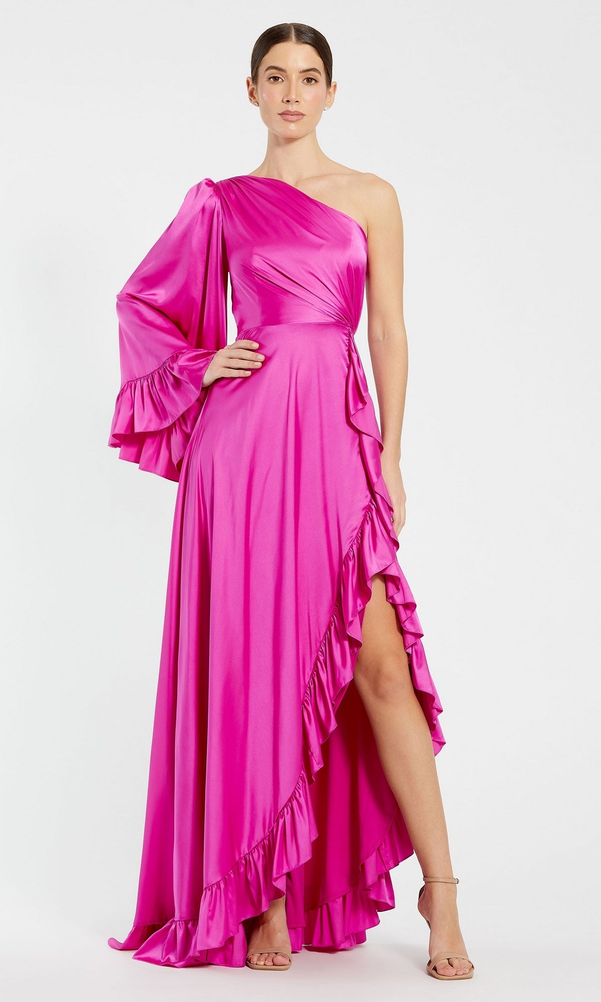A woman wears the Long Formal Dress 55950 by Mac Duggal—a vibrant magenta, one-shoulder gown with ruffled hem and sleeve, high slit—standing against a plain white background.